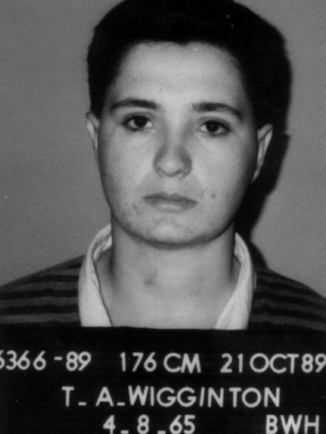 Mugshot of a person with short dark hair, serious expression, and wearing a striped shirt. The image includes identification details at the bottom.